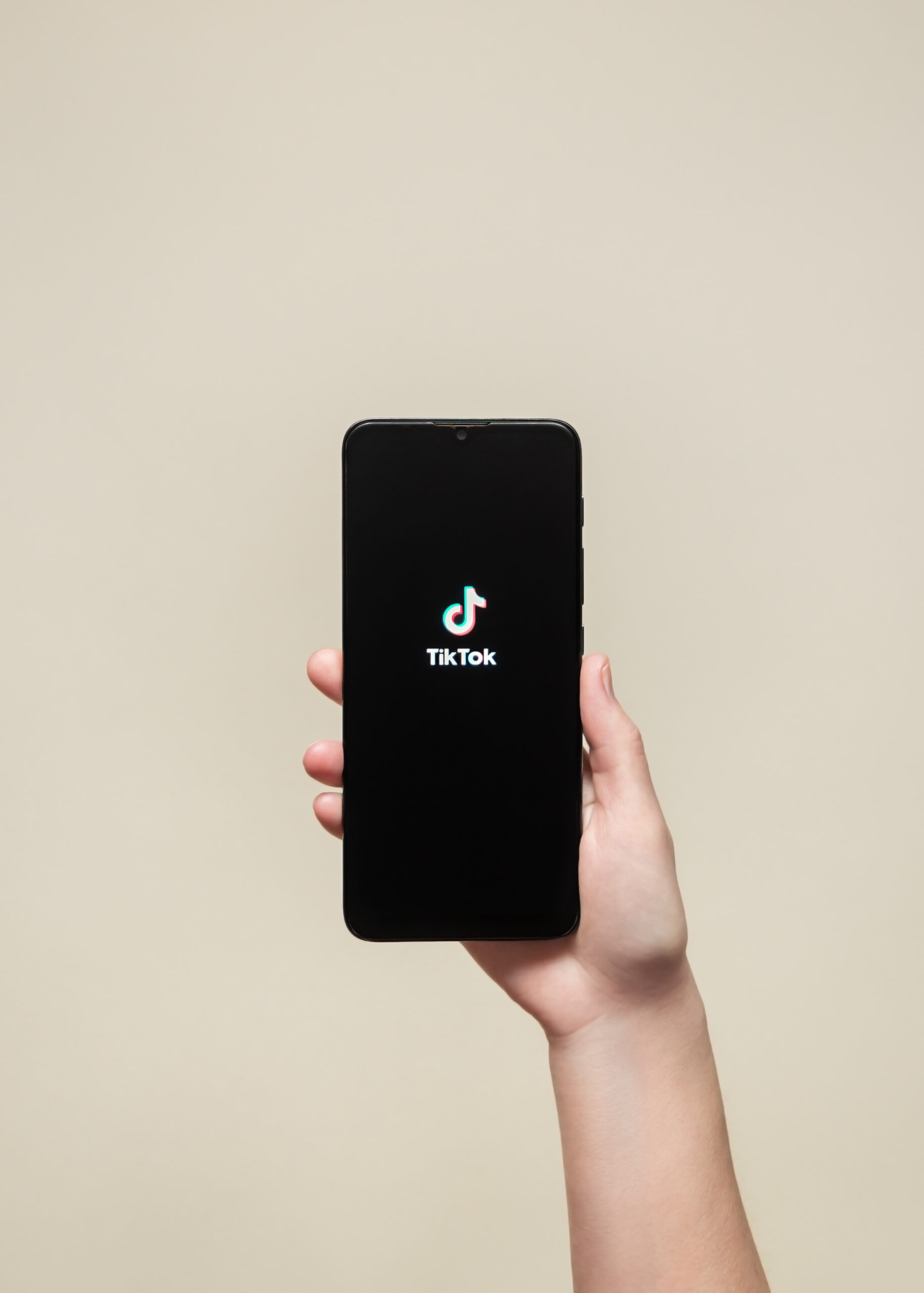hand holding black phone with logo tik tok app screen scaled